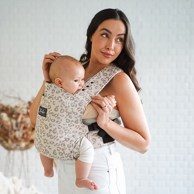 Vue de Face maman portant bébé dans son porte-bébé physiologique Rookie Premium  Imprimé Leopard Beige